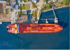 An aerial view of a red cargo vessel alongside a port terminal