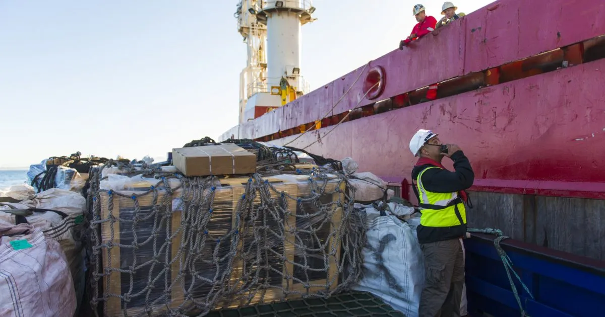 Port personnel overseeing supplies being loaded onto a ship.