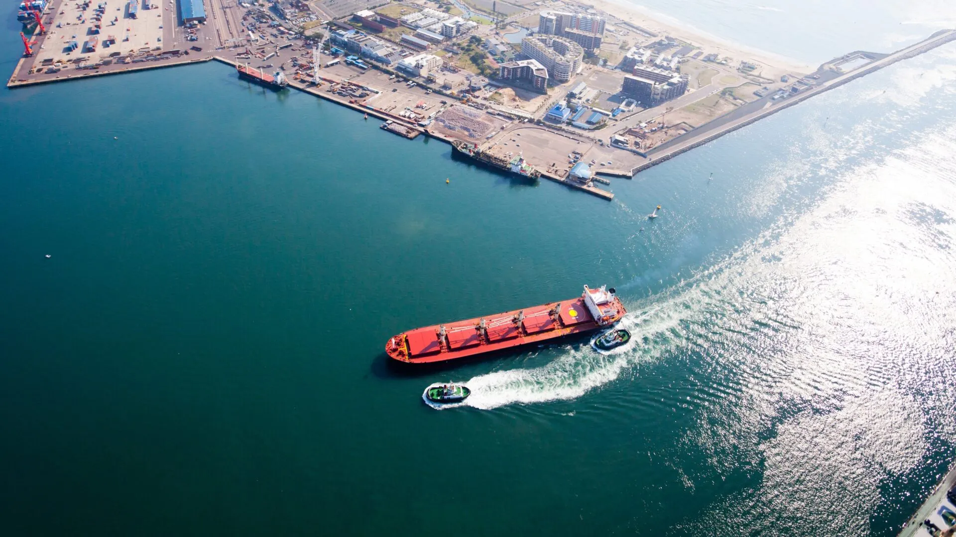 A cargo vessel and tugboat alongside a port terminal.